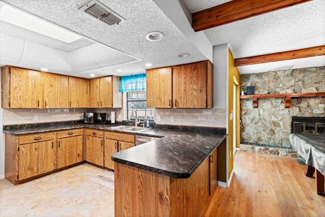 kitchen with a textured ceiling, a sink, visible vents, backsplash, and beam ceiling