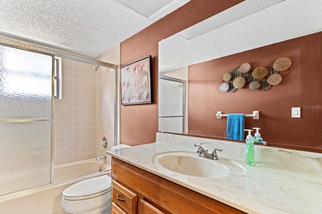 full bathroom featuring a textured ceiling, combined bath / shower with glass door, vanity, and toilet