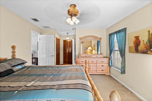 bedroom featuring baseboards, visible vents, light colored carpet, ceiling fan, and a textured ceiling