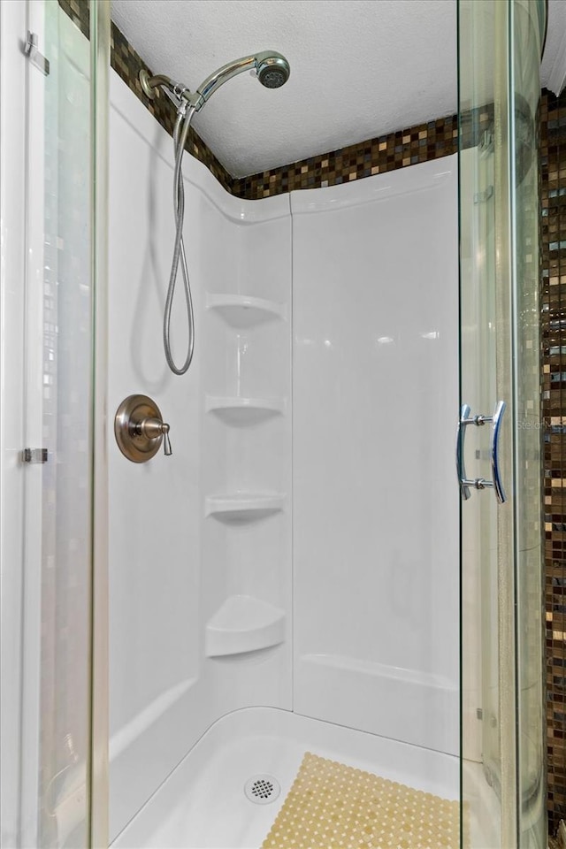 full bath featuring a stall shower and a textured ceiling