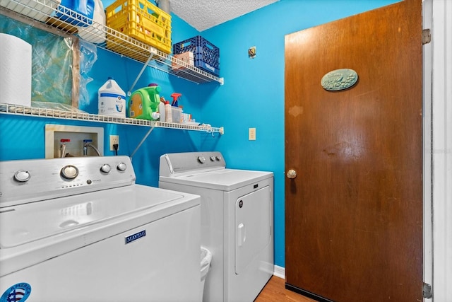 washroom featuring laundry area, separate washer and dryer, a textured ceiling, and wood finished floors