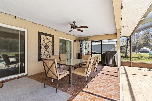 view of patio / terrace featuring a lanai, a grill, a ceiling fan, and outdoor dining space