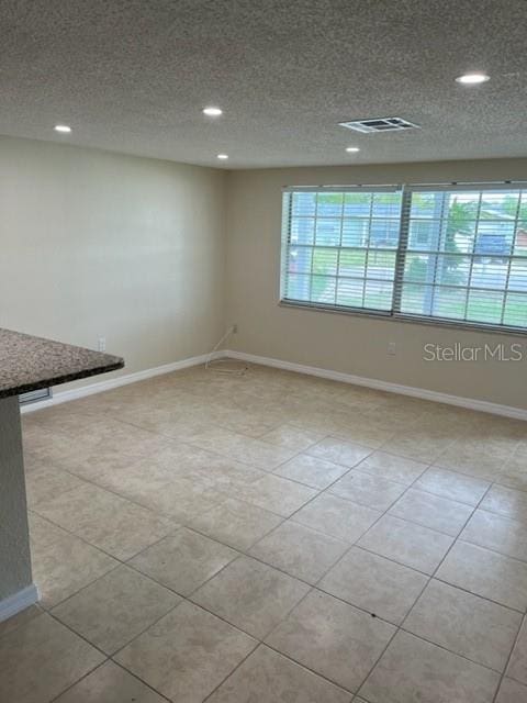 empty room featuring visible vents, plenty of natural light, baseboards, and tile patterned floors