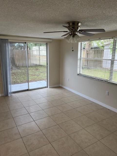 spare room with a healthy amount of sunlight, a textured ceiling, and baseboards