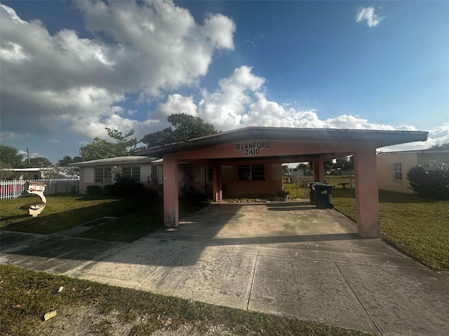 view of front facade with driveway, fence, an attached carport, and a front yard