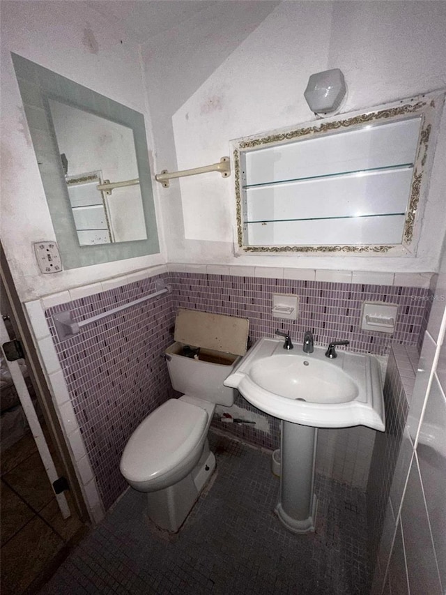 bathroom with wainscoting, tile patterned flooring, toilet, and tile walls