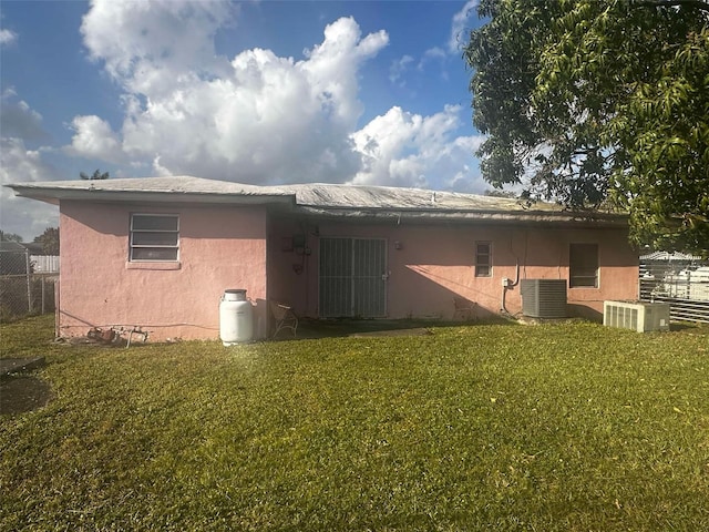 back of property featuring cooling unit, a lawn, and stucco siding