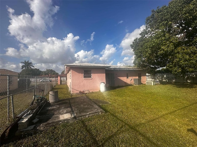 rear view of house with a fenced backyard, a yard, a patio, and stucco siding