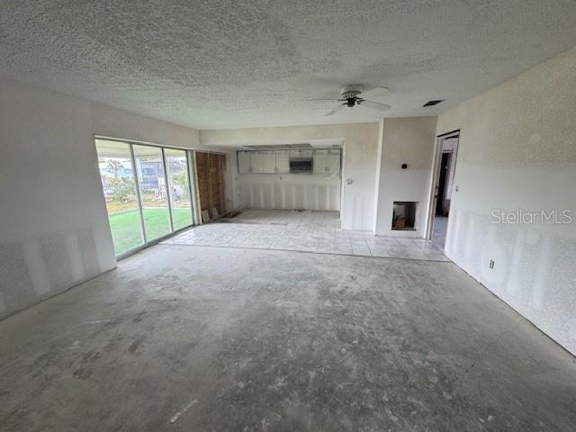 unfurnished living room featuring concrete floors, a ceiling fan, and a textured ceiling