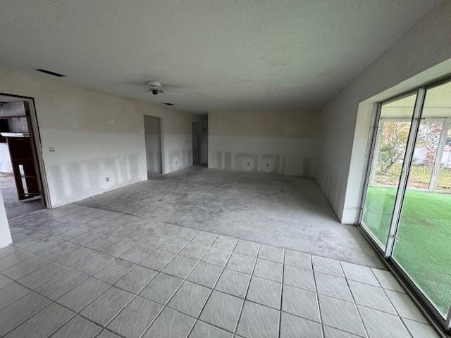 unfurnished living room featuring visible vents, ceiling fan, and a textured ceiling