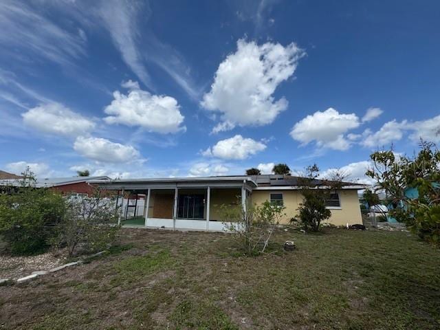 back of property with a lawn, a sunroom, and roof mounted solar panels