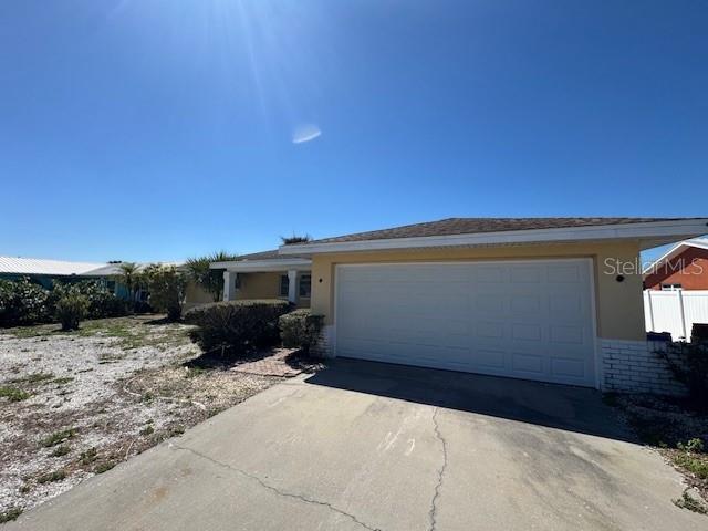 ranch-style home with an attached garage, brick siding, concrete driveway, and stucco siding