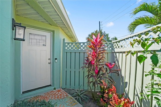 view of exterior entry featuring fence and stucco siding