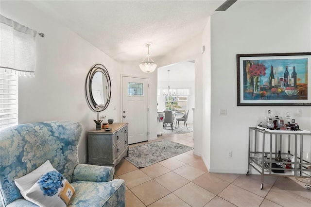 entryway with a textured ceiling, light tile patterned flooring, and a notable chandelier