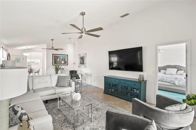 tiled living area featuring visible vents, vaulted ceiling, and ceiling fan with notable chandelier