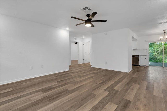 unfurnished living room featuring ceiling fan with notable chandelier, dark wood-type flooring, visible vents, and baseboards