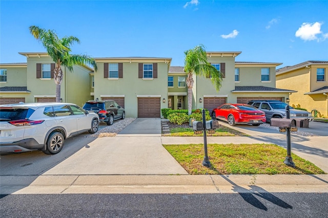 view of property with a garage, driveway, a residential view, and stucco siding