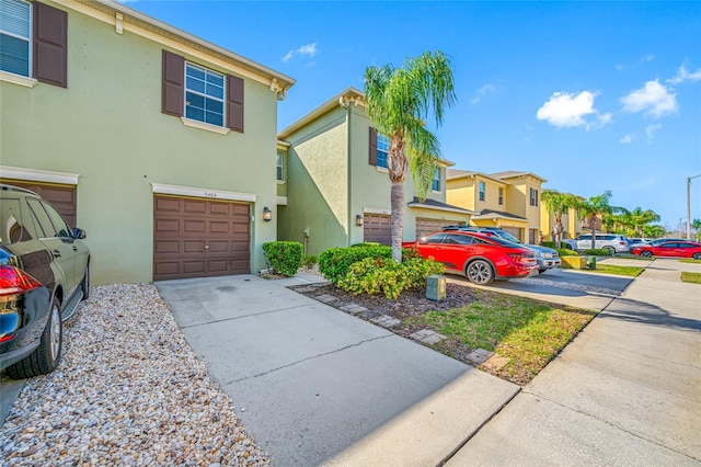 multi unit property featuring a garage, driveway, a residential view, and stucco siding