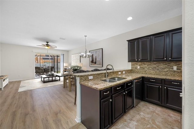 kitchen featuring light stone counters, a sink, visible vents, open floor plan, and backsplash