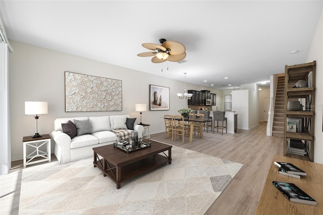 living area featuring light wood finished floors, recessed lighting, visible vents, baseboards, and ceiling fan with notable chandelier