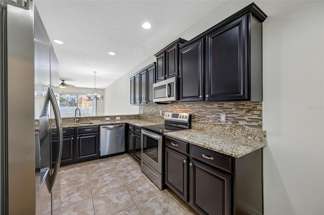 kitchen featuring appliances with stainless steel finishes, backsplash, a sink, and light stone counters