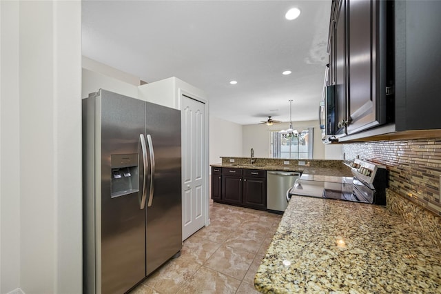 kitchen with light stone counters, a peninsula, a sink, appliances with stainless steel finishes, and tasteful backsplash