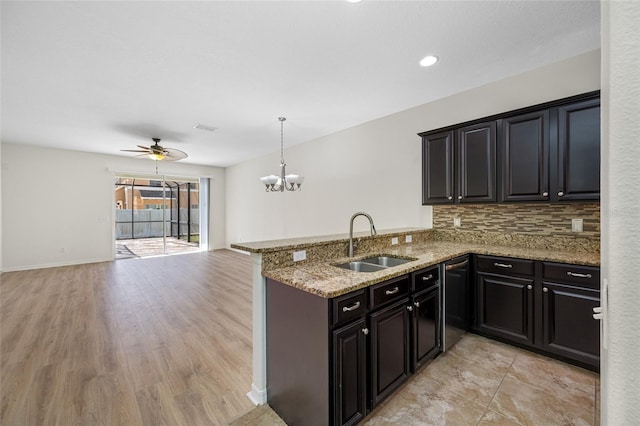 kitchen with light stone counters, backsplash, open floor plan, a sink, and a peninsula