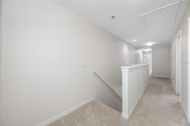 hallway with baseboards, light colored carpet, and an upstairs landing