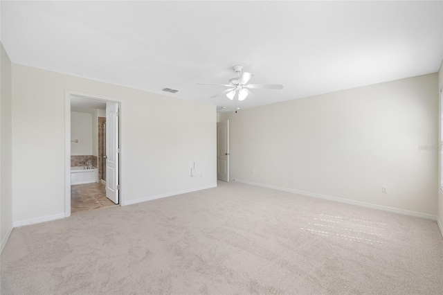 spare room featuring a ceiling fan, light colored carpet, visible vents, and baseboards