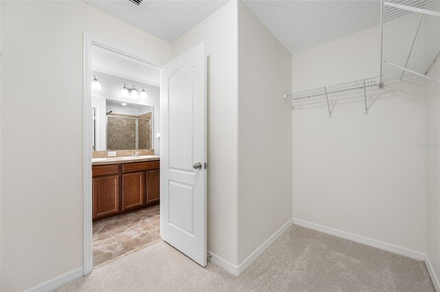 walk in closet featuring light colored carpet