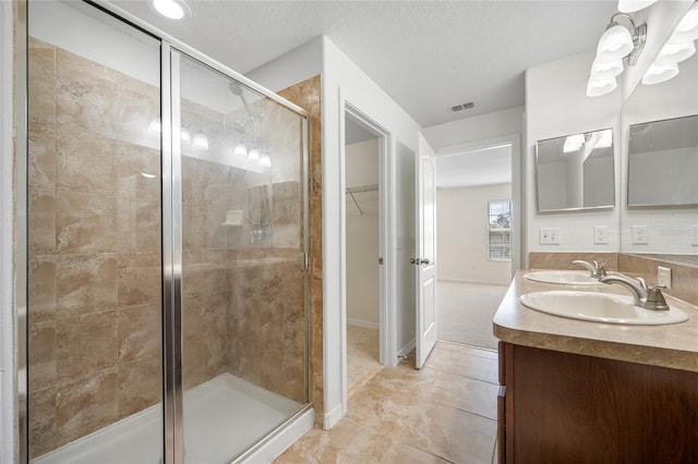 bathroom with visible vents, tile patterned floors, a textured ceiling, a shower stall, and a sink