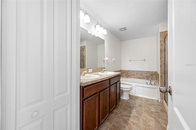 full bath featuring a garden tub, a textured ceiling, visible vents, and a sink