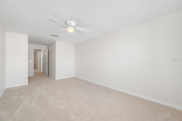 empty room with light carpet, baseboards, visible vents, a ceiling fan, and a textured ceiling