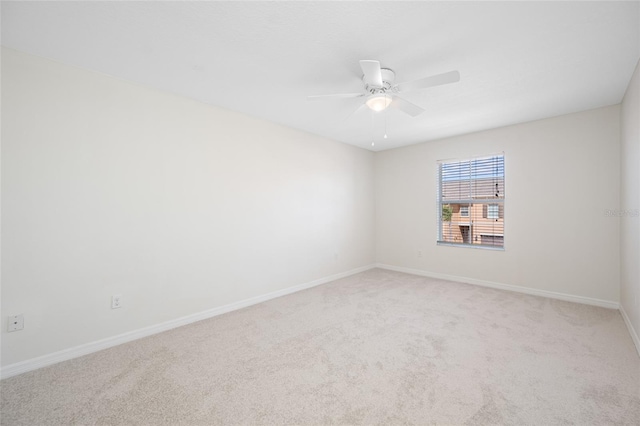 unfurnished room with baseboards, a ceiling fan, and light colored carpet