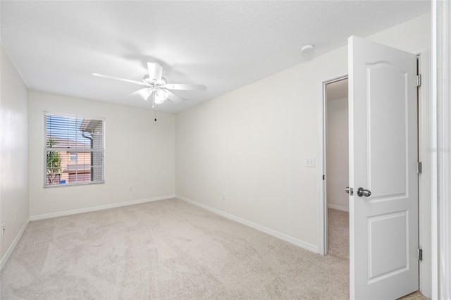 unfurnished room with baseboards, a ceiling fan, and light colored carpet