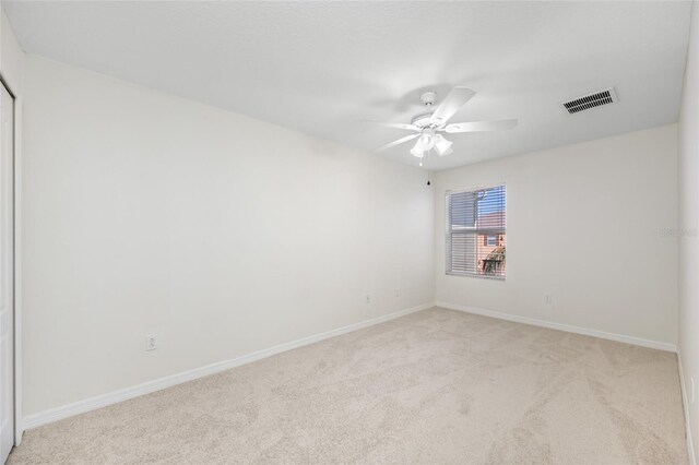 carpeted spare room with ceiling fan, visible vents, and baseboards