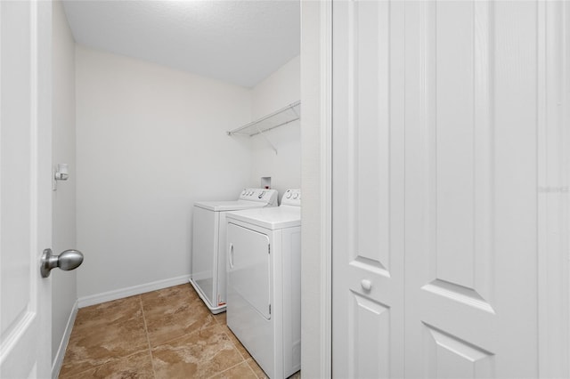 washroom featuring laundry area, separate washer and dryer, and baseboards