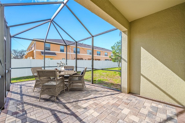 view of patio with outdoor dining area, glass enclosure, and fence