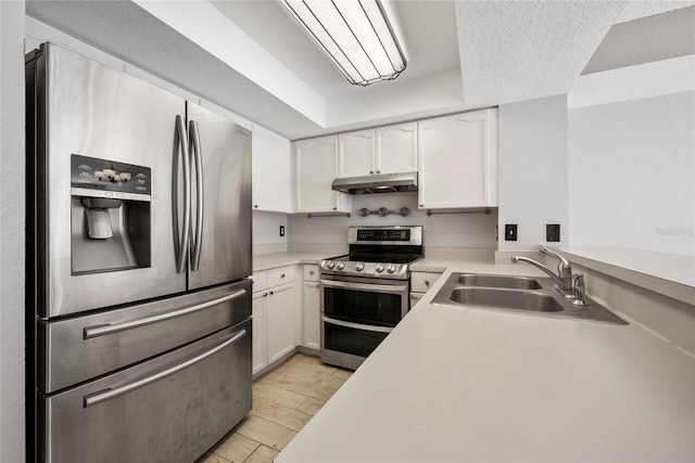 kitchen featuring light countertops, appliances with stainless steel finishes, white cabinets, a sink, and under cabinet range hood