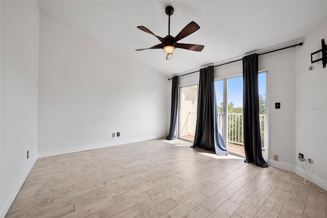 empty room featuring light wood finished floors, lofted ceiling, ceiling fan, a textured ceiling, and baseboards