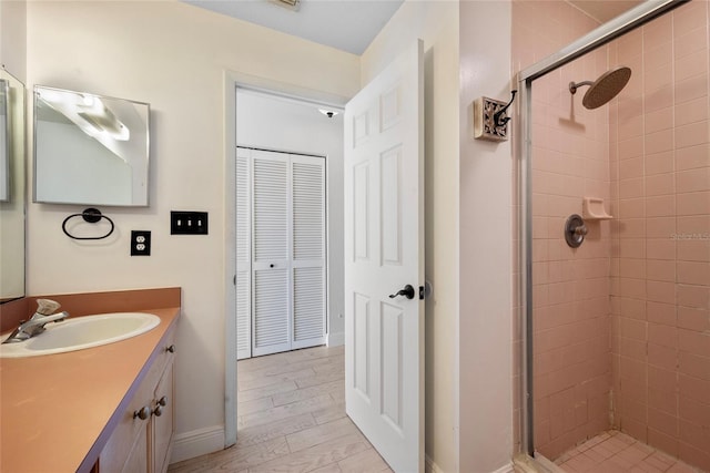 bathroom with a shower stall, baseboards, wood finished floors, and vanity