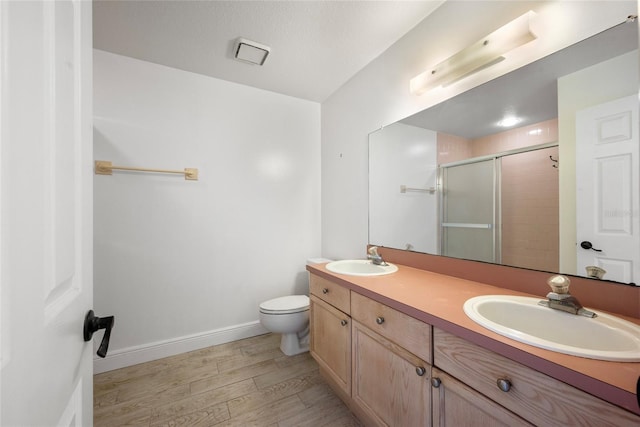 bathroom featuring double vanity, wood finished floors, a stall shower, and a sink