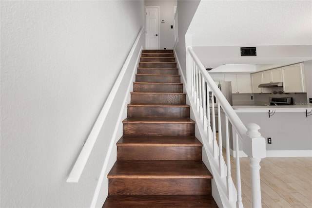 stairway featuring visible vents and wood finished floors