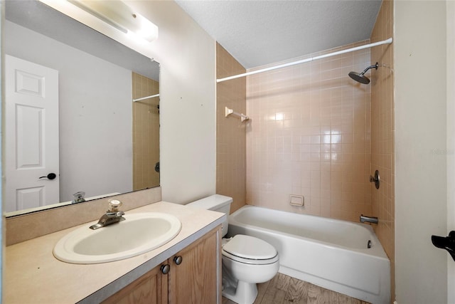 full bathroom with toilet, wood finished floors, tub / shower combination, a textured ceiling, and vanity