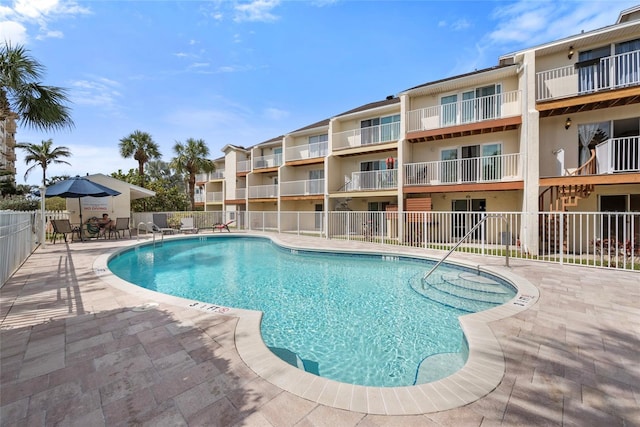 pool with a patio area and fence