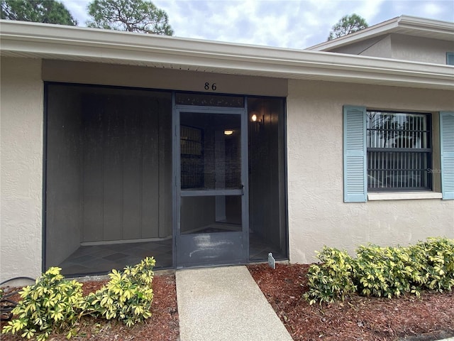 doorway to property featuring stucco siding