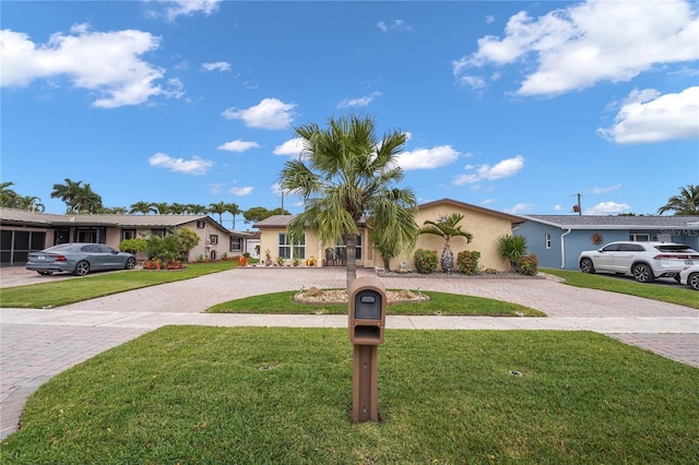 view of front of home with decorative driveway, a front lawn, and stucco siding