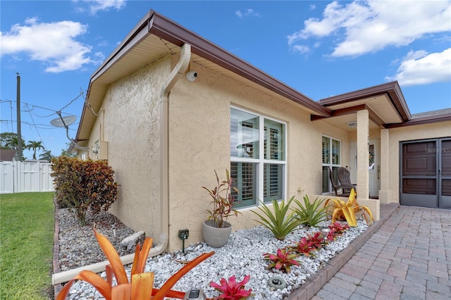 view of home's exterior with a yard, fence, and stucco siding