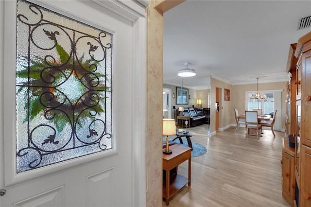 entrance foyer with light wood finished floors, baseboards, visible vents, ornamental molding, and an inviting chandelier