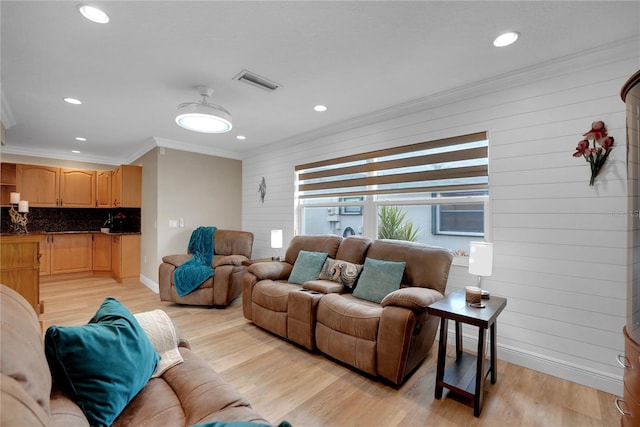 living area featuring crown molding, wood walls, visible vents, and light wood-style floors